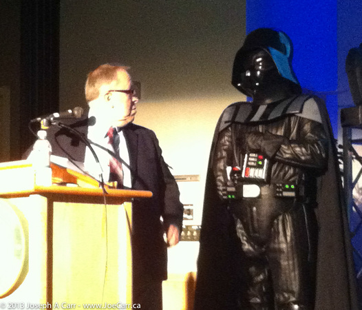Minister Michael Gravelle makes a few remarks while Darth Vader look on