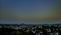 Blue hour with a smoky sunset highlighting a Quarter Moon over the city