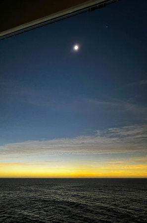 Fully-eclipsed Sun with Venus to the right and Jupiter to the left - over the ocean and dark skies